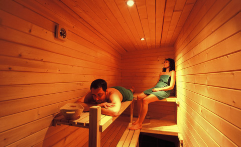 To personer slapper af i en varm sauna med trævægge på Dihan Evasion - Lodges Bretagne, ideel til glamping.