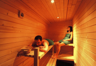 Dos personas se relajan en una sauna de madera en Dihan Evasion - Lodges Bretagne, ideal para glamping o camping.