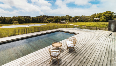 Wooden terrace with pool and wicker chairs at Dihan Evasion - Lodges Bretagne glamping in scenic nature.
