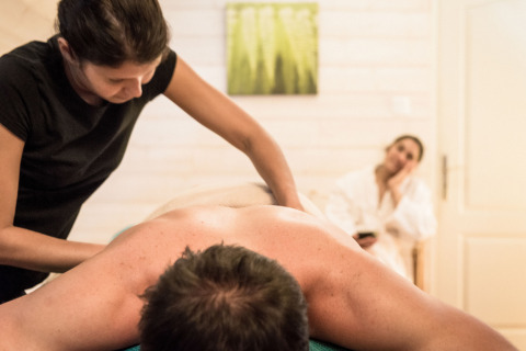 Massage relaxant au spa de Dihan Evasion - Lodges Bretagne, une femme en peignoir en arrière-plan.