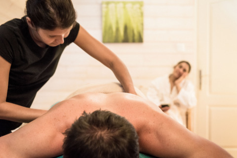 Ontspannende massage in de spa van Dihan Evasion - Lodges Bretagne, met een vrouw in badjas op de achtergrond.