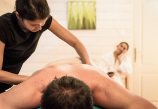 Massaggio rilassante nella spa di Dihan Evasion - Lodges Bretagne, con donna in accappatoio sullo sfondo.