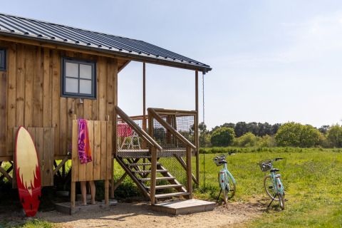 Glamping à Dihan Evasion - Lodges Bretagne avec cabane en bois, douche extérieure, vélos et planche de surf.