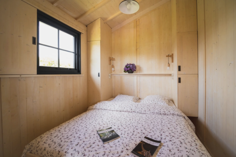 Chambre chaleureuse en bois avec lit double et fenêtre chez Dihan Evasion - Lodges Bretagne.