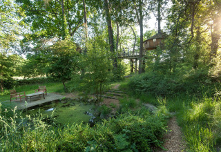 Boomhut tussen groen met terras en zitje bij een vijver bij Dihan Evasion - Lodges Bretagne, glamping accommodatie.