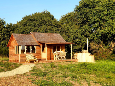 Wooden glamping cabin with porch and outdoor hot tub at Dihan Evasion - Lodges Bretagne, surrounded by nature.