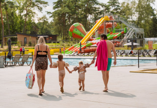 Gezin loopt richting zwembad bij Vakantiepark Ommerland – Safaritenten Overijssel met waterglijbanen achter.
