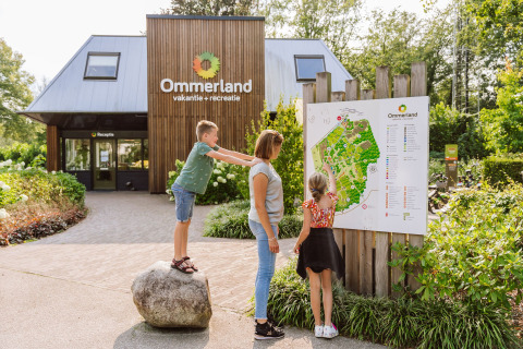 Familie betrachtet eine Karte am Eingang des Vakantiepark Ommerland Safaritenten Overijssel Campingplatzes.