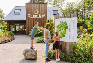 Family checks the map at the entrance of Vakantiepark Ommerland Safaritenten Overijssel glamping site.