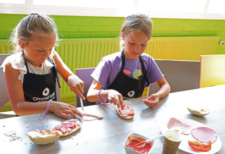 Deux enfants préparent à manger ensemble sur une table au Vakantiepark Ommerland – Safaritenten Overijssel.