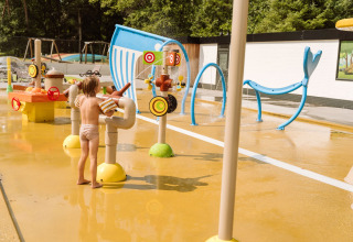 Enfant jouant sur une aire de jeux aquatique par une journée ensoleillée chez Vakantiepark Ommerland Safaritenten Overijssel.