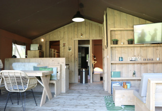 Interno di una tenda safari al Vakantiepark Ommerland in Overijssel, arredato con mobili in legno accoglienti.