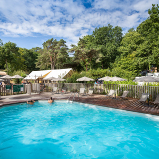 Piscine extérieure au Huttopia Douarnenez – Glamping Bretagne, entourée de transats et d'une végétation luxuriante.