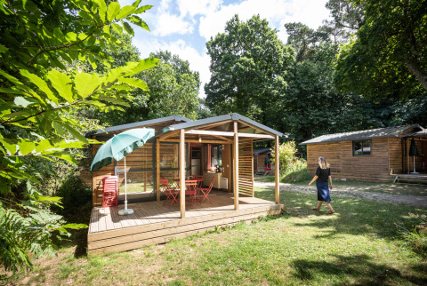 Glamping accommodatie bij Huttopia Douarnenez – Glamping Bretagne, houten chalet omringd door groen.