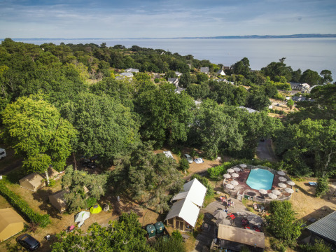 Luftfoto af Huttopia Douarnenez glamping i Bretagne med telte, swimmingpool og udsigt over havet.