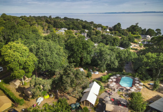 Luftfoto af Huttopia Douarnenez glamping i Bretagne med telte, swimmingpool og udsigt over havet.