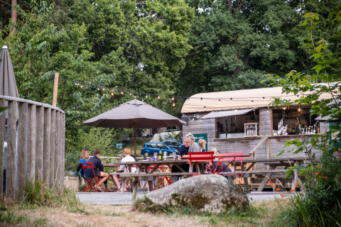 Zona de comedor exterior en Huttopia Douarnenez – Glamping Bretagne con familias y naturaleza verde.