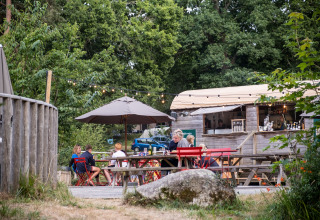 Espace de restauration extérieure à Huttopia Douarnenez – Glamping Bretagne avec familles et nature verdoyante.