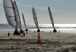 Gruppo di velieri terrestri sulla spiaggia vicino a Huttopia Douarnenez – Glamping Bretagne, mare sullo sfondo.