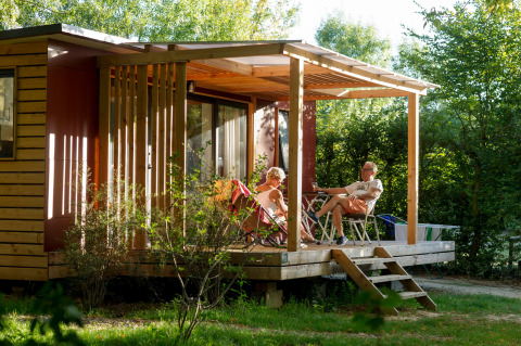 Deux personnes se détendent sur la terrasse en bois du Huttopia Saumur, glamping en Pays de la Loire.