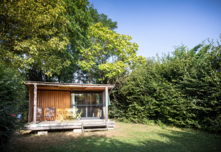 Alloggio glamping in cabina da Huttopia Saumur, Pays de la Loire, immerso nel verde degli alberi.