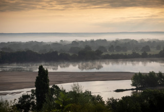 Brume matinale sur la rivière près de Huttopia Saumur - Glamping Pays de la Loire, paysage paisible de France.
