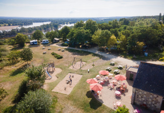 Vista aérea de Huttopia Saumur Glamping en Pays de la Loire con parque infantil, caravanas y terraza.