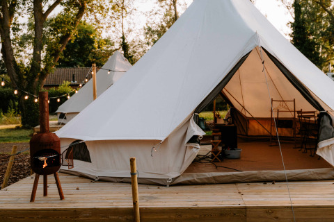 Glampingtenten bij Boszee in West-Vlaanderen met houten terras en sfeerverlichting tijdens de avond.