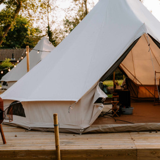 Tende di glamping a Boszee, West-Vlaanderen, Belgio, con terrazza in legno e luci accoglienti serali.