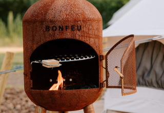 Stufa da esterno arrugginita vicino a tenda glamping di Boszee - Glampingtenten West-Vlaanderen.