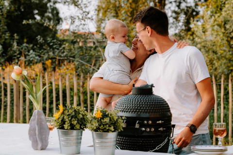 Famiglia si gode il tempo insieme vicino al barbecue e fiori al Boszee Glampingtenten West-Vlaanderen.