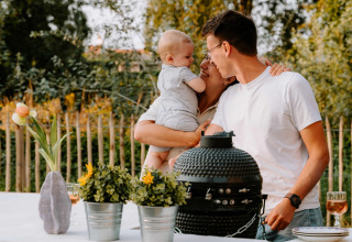 Familia comparte tiempo al aire libre junto a barbacoa y flores en Boszee Glampingtenten West-Vlaanderen.