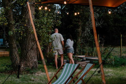 Dos personas disfrutan de una tarde de verano en Boszee - Glampingtenten West-Vlaanderen entre la naturaleza.