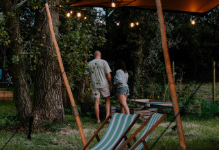Deux personnes profitent d'une soirée d'été au Boszee - Glampingtenten West-Vlaanderen en pleine nature.