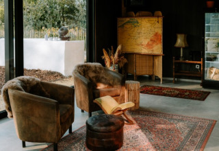 Cozy glamping lounge with comfy chairs, rugs, and nature views at Boszee Glampingtenten West-Vlaanderen.