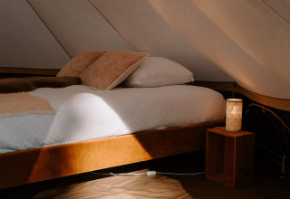 Sfeervolle glampingtent met zacht bed en gezellige lamp bij Boszee - Glampingtenten West-Vlaanderen.