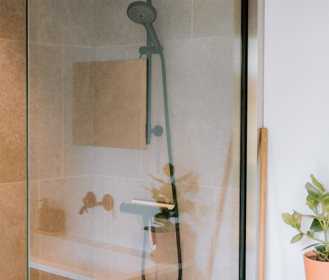 Ducha moderna con mampara de vidrio en Boszee Glampingtenten West-Vlaanderen, con plantas y estilo acogedor.
