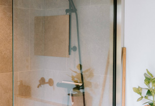 Moderne douche met glazen wand in Boszee Glampingtenten West-Vlaanderen, met planten en strak design.