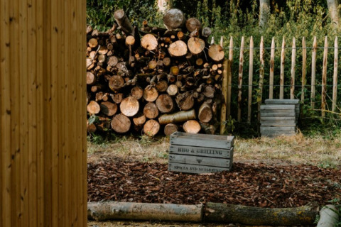 Gestapeld hout, omheining en houten kisten bij Boszee Glampingtenten West-Vlaanderen in de natuur.