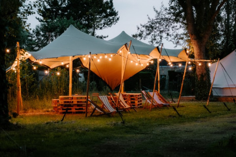 Espace glamping Boszee - Glampingtenten West-Vlaanderen avec tentes, guirlandes lumineuses et chaises longues.