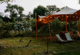 Glampingtent met sfeerverlichting en ligstoelen bij Boszee - Glampingtenten West-Vlaanderen in de tuin.