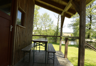Veranda in legno con panca e tavolo a Kano & Kamp Aqua Hema- Blokhutten Beieren, vista sul lago.