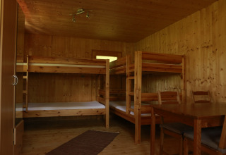 Wooden cabin with two bunk beds, dining table and chairs, glamping accommodation at Kano & Kamp Aqua Hema, Bavaria.