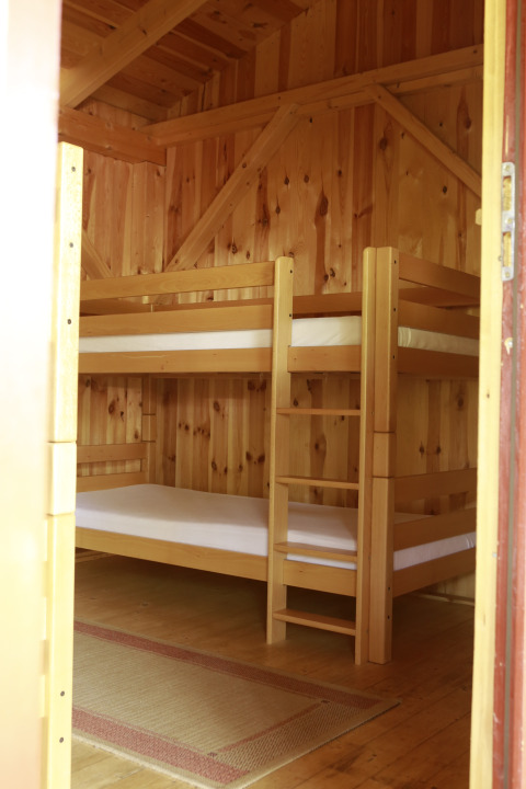 Interior view of a wooden cabin with bunk beds and rug, Kano & Kamp Aqua Hema- Blokhutten Beieren.