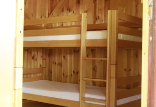 Vue intérieure d'une cabane en bois avec lits superposés et tapis, Kano & Kamp Aqua Hema- Blokhutten Beieren.