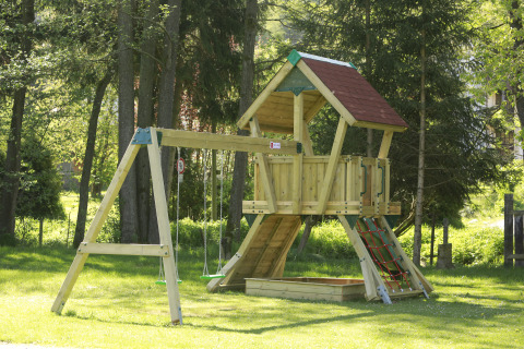 Wooden playground set with swings, climbing net and sandbox at Kano & Kamp Aqua Hema- Blokhutten Beieren.