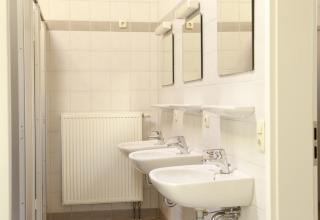 Rene fælles badeværelsesfaciliteter med håndvaske, spejle og radiator på Kano & Kamp Aqua Hema- Blokhutten Beieren.