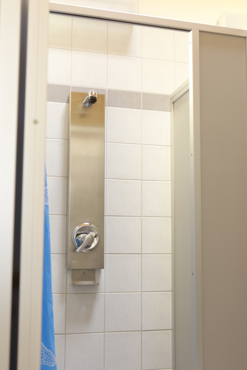 Ducha con azulejos blancos y grifería moderna en Kano & Kamp Aqua Hema- Blokhutten Beieren camping.