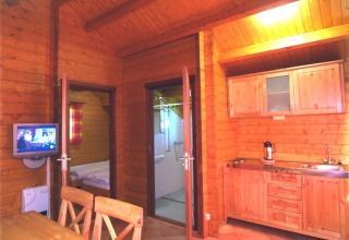 Interni in legno di una sistemazione glamping con cucina, TV e accesso a camera e bagno all’Eifelidyll.