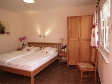 Cozy glamping room at Eifelidyll with double bed, wooden furniture and flowers, in Rhineland-Palatinate.
